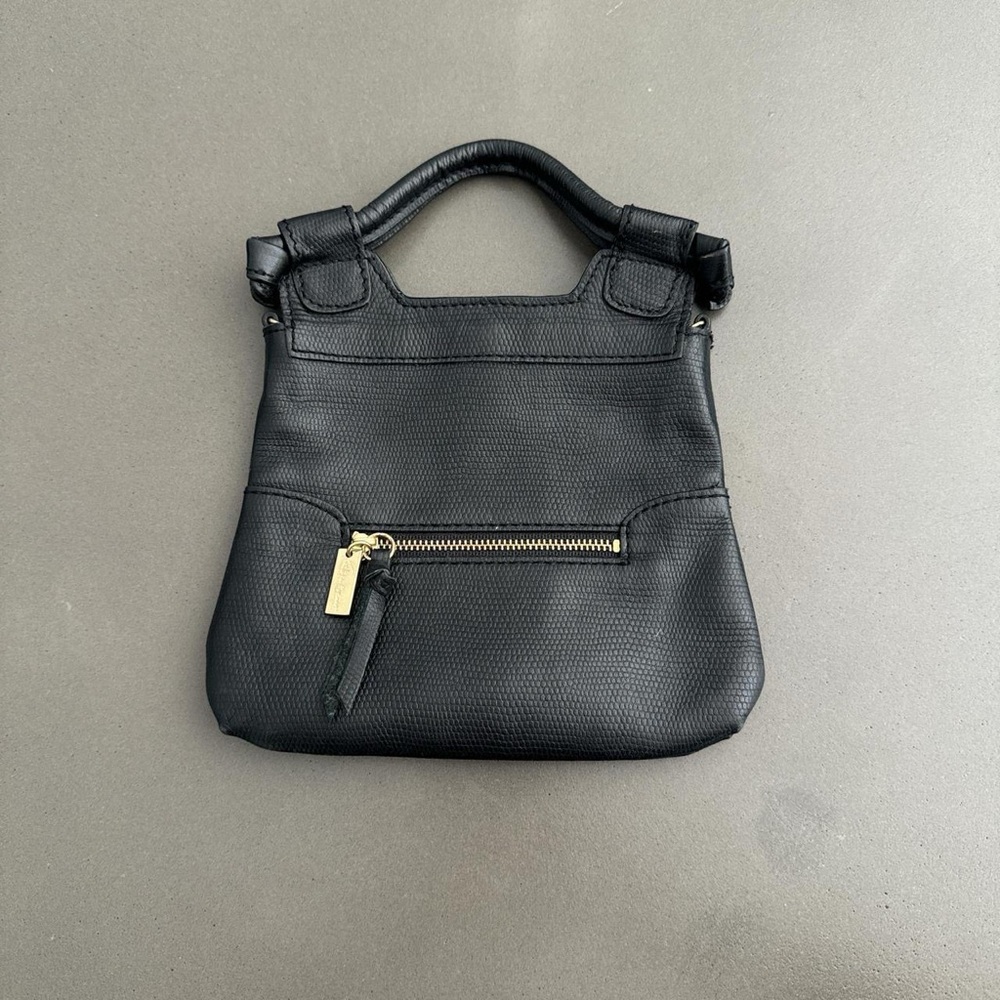 black leather purse with gold hardware and a gold chain that’s optional to wear.